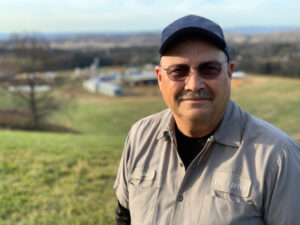 Photo of producer John Litz with his farm operation in the background.