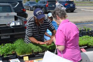 Mike Beauchamp shows a customer some products at a farmers market.