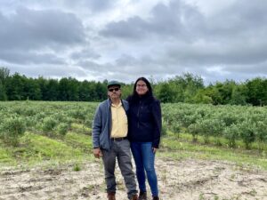 Sigifredo Morales-Martinez and daughter Yaraici Morales stand in front of field of blueberry bushes.