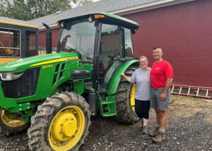 Allison and Chris stand next to a green tractor.