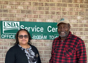 Latoyia Elliott stands to the left and Elisha Barnes on the right with a sign behind them that says "USDA Service Center"