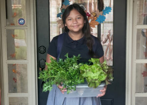Trinity Waguespack holds a container full of leafy greens.