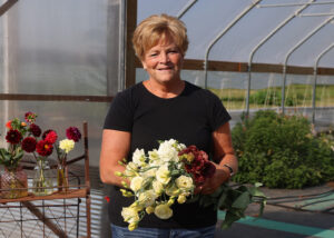 Rhonda Larson stands in front of her high tunnel with a bouquet of cut flowers
