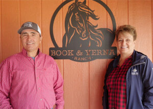 Book St. Goddard and wife Verna Billedeaux stand by a sign saying "Book & Verna Ranch"